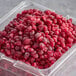 A plastic container of IQF organic pomegranate arils with a white label.