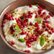 A bowl of yogurt with organic pomegranate arils and mint leaves.
