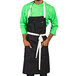 A black Uncommon Chef bib apron with natural webbing and pockets.