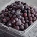 A plastic container of 30 lb. IQF organic blueberries on a table.