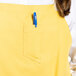 A person wearing a yellow Uncommon Chef Vibe Bib Apron with a pen in the pocket.