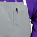 The front pocket of a gray Uncommon Chef Vibe Bib Apron with a pen in it.