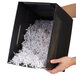 A person holding a black box with shredded paper.