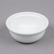 A Tuxton white china bowl on a gray surface.