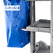 A Carlisle janitorial cart with a blue nylon bag on a metal shelf.