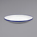 A close up of a Crow Canyon Home white enamelware plate with a blue rim.
