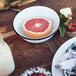 A white Crow Canyon Home enamelware bowl with a half of a grapefruit in it.