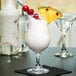 A Libbey Poco Grande glass filled with a white drink and garnished with pineapple and a cherry.
