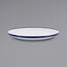 A close up of a Crow Canyon Home white enamelware plate with blue rim.