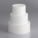 A stack of three white cylindrical foam cake dummies.