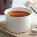 A close-up of a white Choice paper food cup filled with soup.