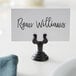 An American Metalcraft black metal low profile harp table card holder with a place card that reads "Ryan Williams" on a white table.