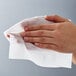 A hand holding a white Fresh Towel moist towelette.