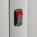 A close-up of a red and black switch on a metal door.