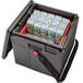 A Cambro black insulated milk crate carrier with a black handle and lid with white and green milk cartons inside.