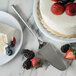 A white cake with a slice served on a plate with strawberries and blueberries using a Carlisle Terra stainless steel pastry server.