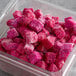 A plastic container of IQF frozen diced pink pitaya dragon fruit cubes.