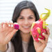 A woman holding up a pink cube of Pitaya Foods IQF frozen diced pitaya dragon fruit.