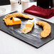 An American Metalcraft black faux slate melamine platter with cheese and crackers on it.