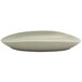 A close-up of a Front of the House Tides porcelain oval plate with a curved edge.
