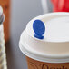 A Royal Paper blue beverage stirrer in a coffee cup with a lid.