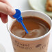 A hand using a Royal Paper blue plastic beverage stirrer in a cup of coffee.
