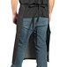A person wearing a black Uncommon Chef Uptown Bistro apron with a black cat design.
