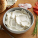 A white bowl of Smithfield cream cheese spread with a spoon.