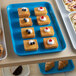 A blue Cambro market tray of pastries on a table in a bakery display.