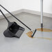 A broom and a bucket with liquid on the floor cleaning a brown stain.