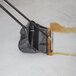 A black plastic bucket on the floor with brown liquid and a Rubbermaid Lobby Pro Wet / Dry Cleaning Wand Squeegee inside.