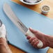 A person using a Dexter-Russell Sani-Safe fish splitter knife to cut white fish on a cutting board.