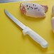 A Dexter-Russell Sani-Safe 6" Wide Fillet Knife cutting chicken.