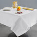 A white Hoffmaster Cellutex tablecloth on a table with plates and food on it.