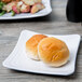A white Milano Melamine square plate with buns on it.