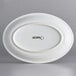 An Acopa Capri oval stoneware platter in white with a white border.