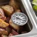 A Comark pocket probe thermometer in a pan of potatoes.