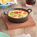 A Valor pre-seasoned mini cast iron bowl filled with chili, cheese, and jalapenos on a wood table.