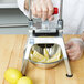 A hand in a plastic glove uses a Vollrath Redco InstaCut 3.5 to cut lemons into wedges.