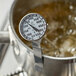 A Comark T550/38A pocket probe thermometer gauge in a pot of boiling liquid.
