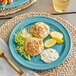 A Acopa Capri stoneware plate with crab cakes and lemon slices on a table.