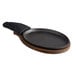 A black oval cast iron fajita skillet with a wooden handle.
