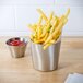 A silver stainless steel container with french fries and ketchup.