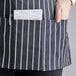 A person wearing a Choice black and white chalk stripe apron with three pockets holding a business card.