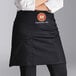A woman wearing a black Choice half bistro apron with a badge on it.