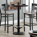 A Lancaster Table & Seating black cast iron bar height table base with foot rest and self-leveling feet.