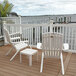 Two white Grosfillex Westport resin Adirondack chairs on a deck overlooking water.