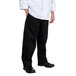 A man wearing Chef Revival black chef pants and a white shirt.