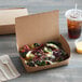 A Fold-Pak Bio-Plus Dine take-out box with a salad inside next to a drink and utensils.