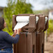 A woman putting a roll of paper towels on a brown Cambro portable handwash station.